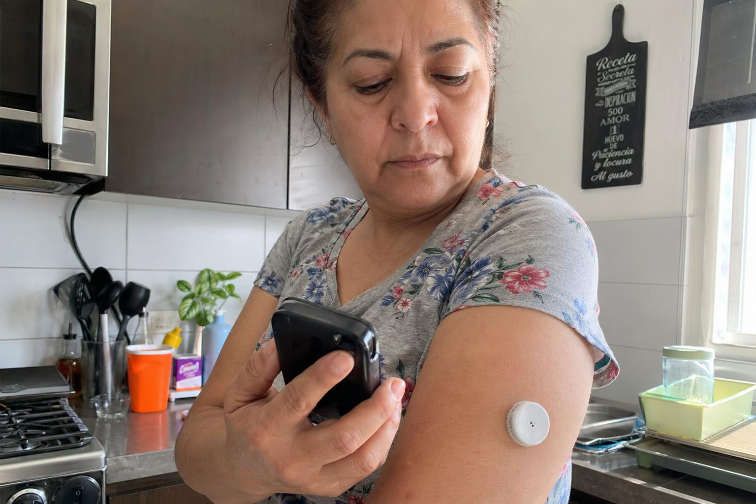Mujer revisando su sensor de glucosa continua con un teléfono